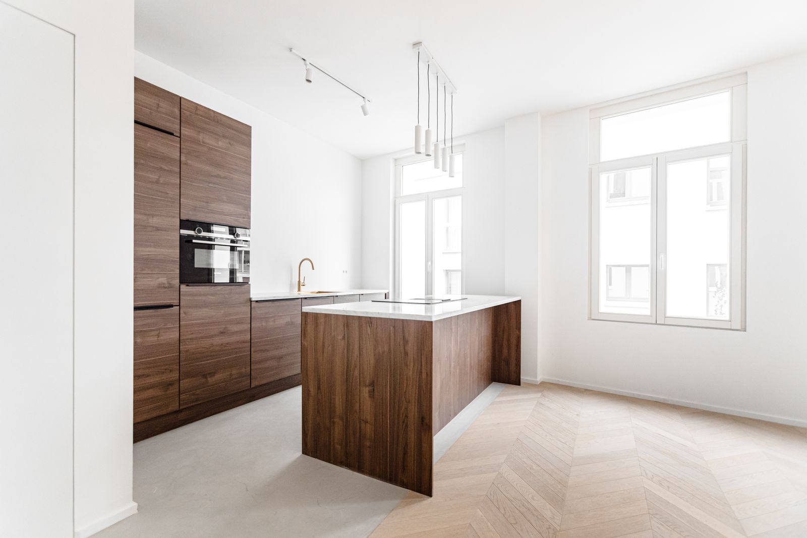 Keuken in notelaar met een eiland met wit marmeren blad, op visgraatparket